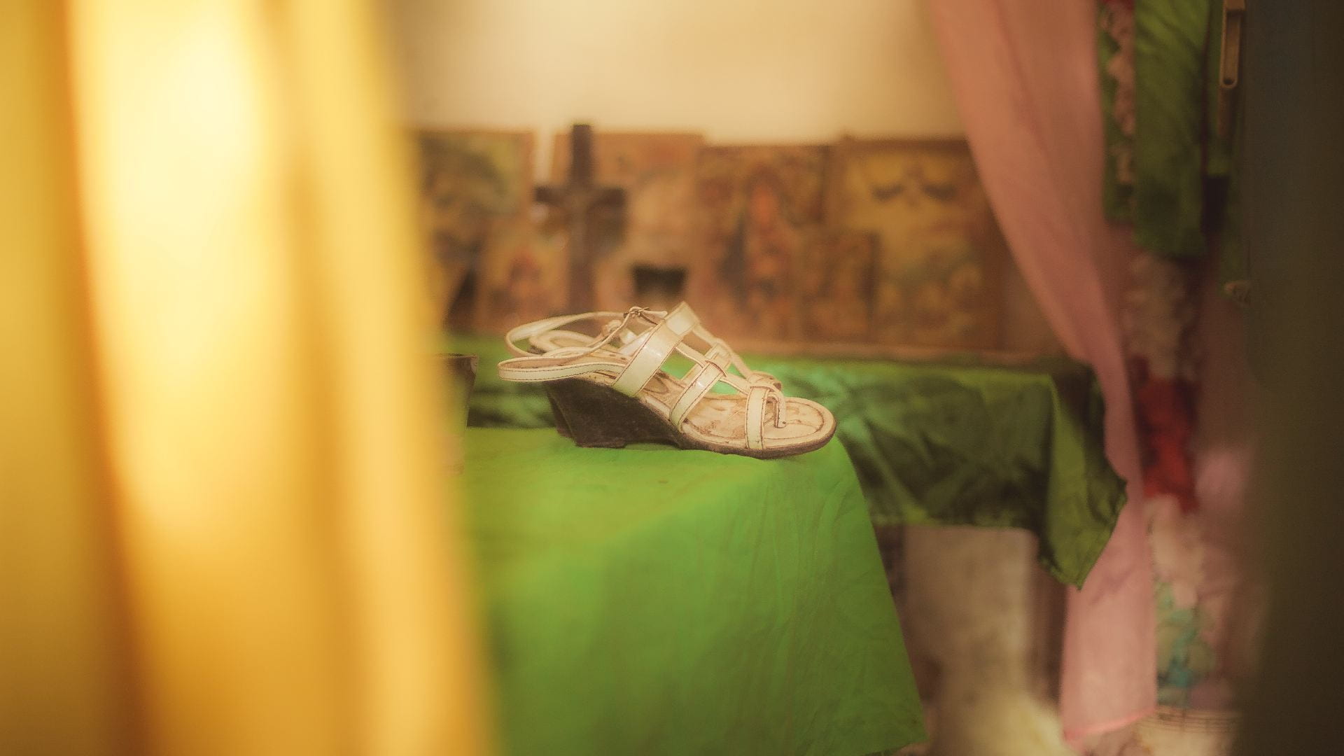 A pair of champagne-colored sandals lie atop green fabric.